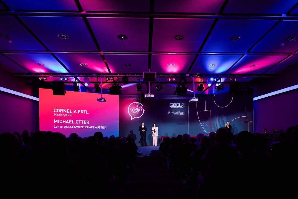Bühne beim Exporttag 2025 mit der Einblendung „Cornelia Ertl, Moderation“
